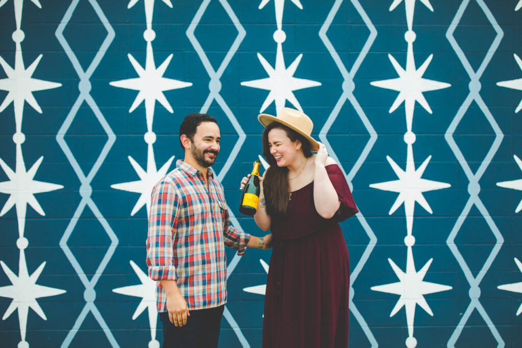 couple laugh in front of star wall