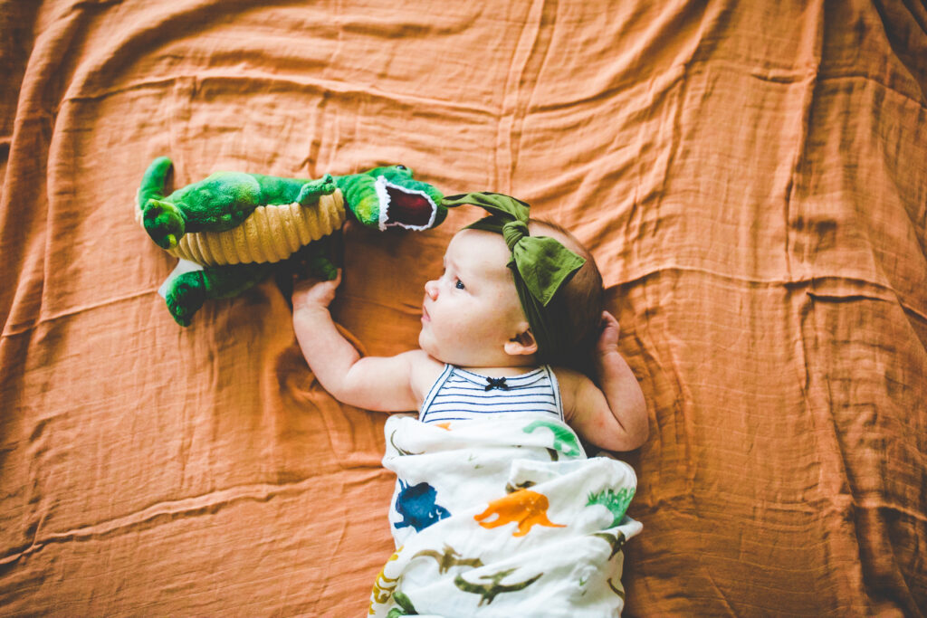 newborn with stuffed dinosaur
