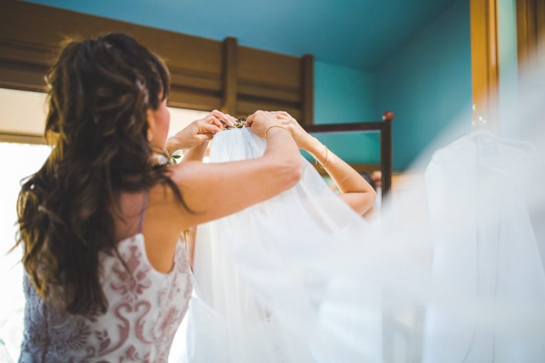 bride puts on wedding veil at Cooper chapel, unique documentary wedding photography in Northwest Arkansas